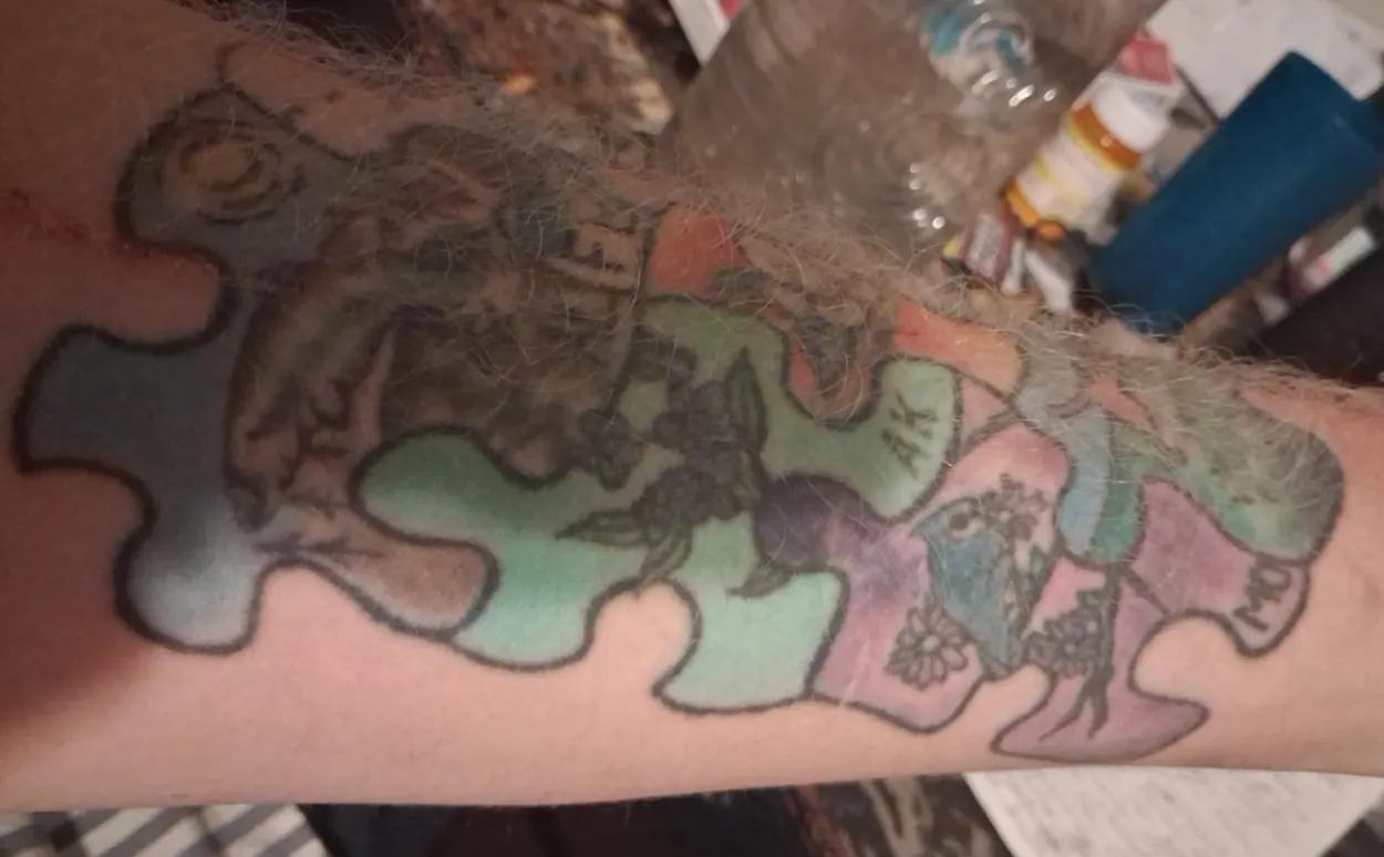 Tattoo detail with interlocking puzzle pieces, animal motifs and botanical designs
